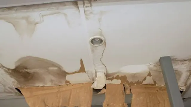 Water-damaged ceiling with sagging panels around a light fixture